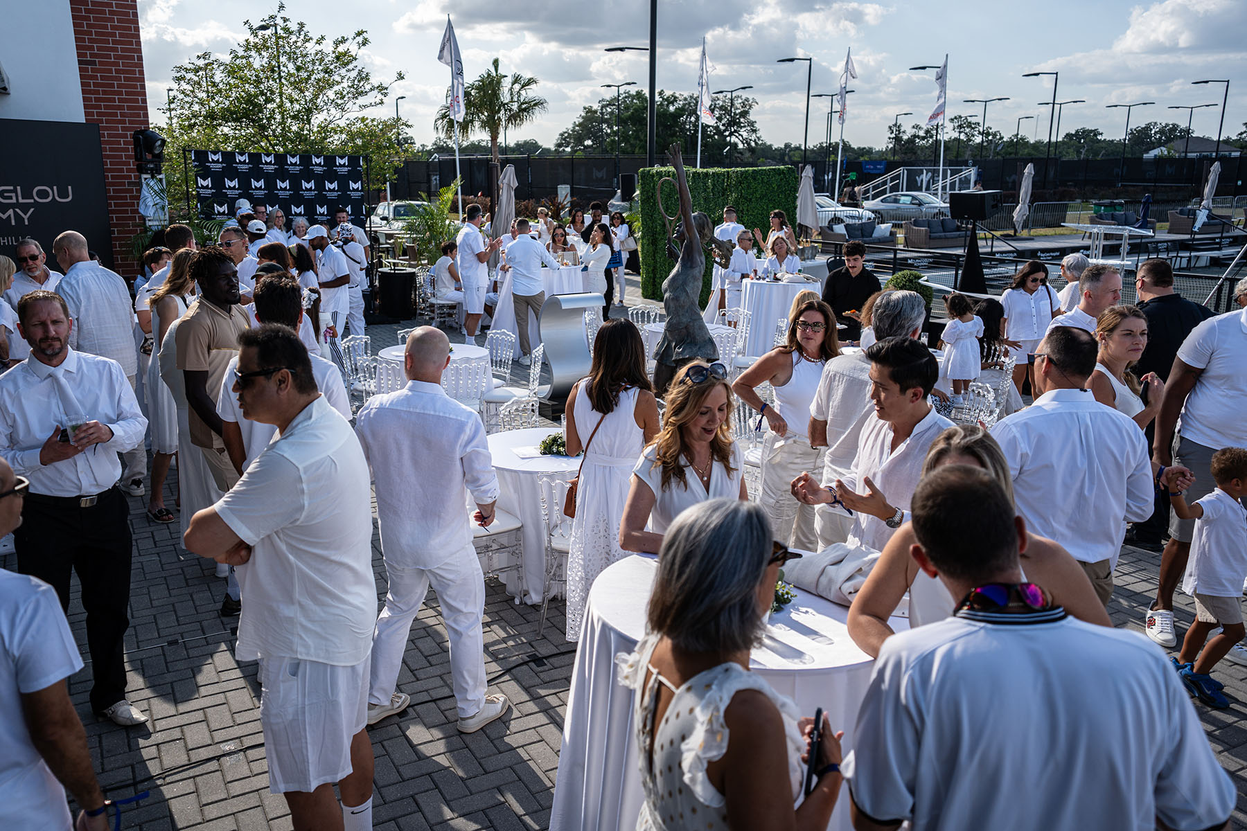Guests celebrating the grand opening of Mouratoglou Academy Zephyrhills during an outdoor reception in Florida.